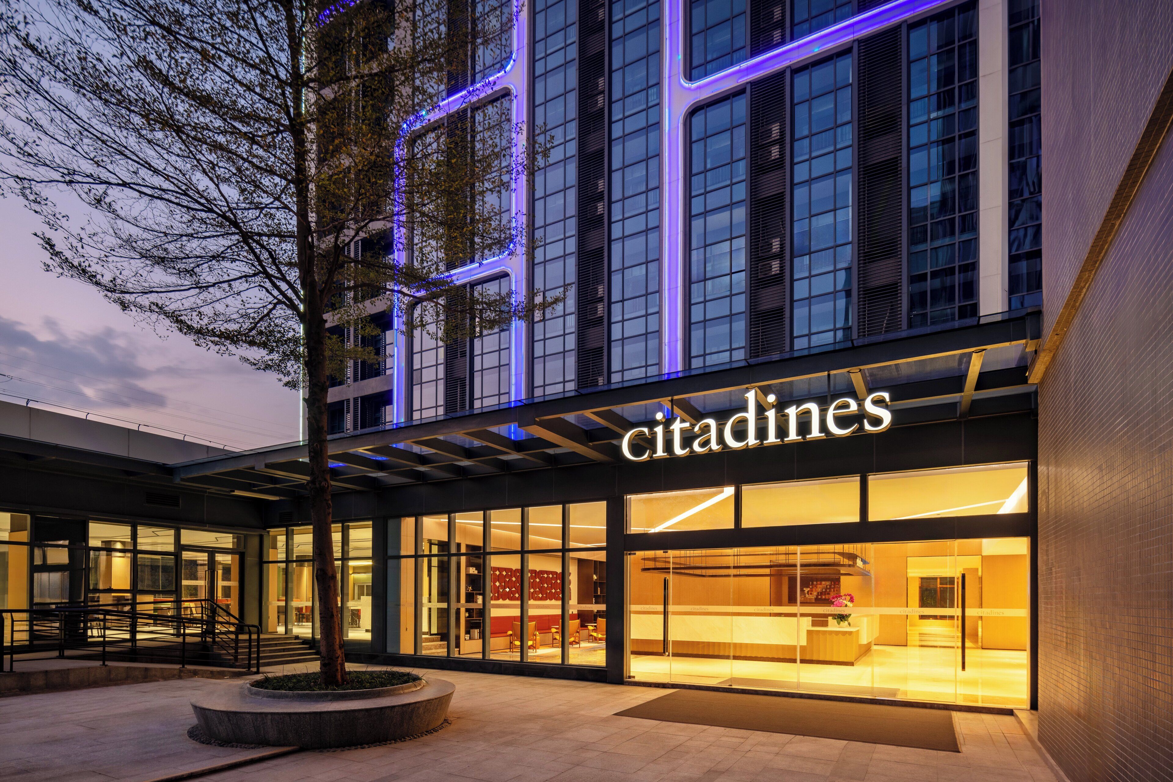 Um edifício moderno com fachada de vidro e uma placa com a inscrição "citadines".