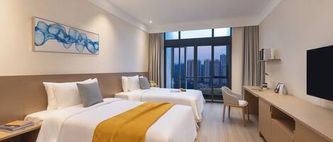 A hotel room with two beds, a desk, a chair, a TV, and a large window with a city view.