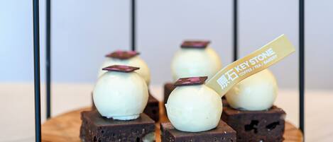 A dessert display with spherical treats on a wooden board, supported by a metal stand.