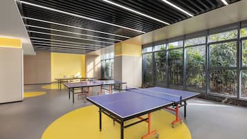 A modern indoor space with ping pong tables, large windows, and a yellow floor.