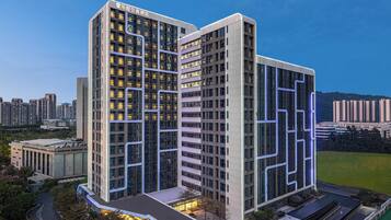 A modern hotel with a prominent glass facade, multiple floors, and a well-lit entrance.