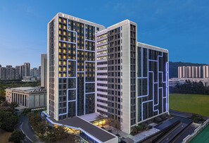 A modern hotel with a prominent glass facade, multiple floors, and a well-lit entrance. - Keymore Residence Guangzhou (Guangzhou)