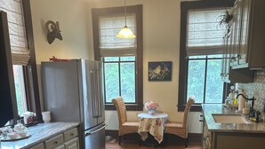 A kitchen with a refrigerator, stove, and dining area with chairs and a table.