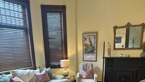 A cozy living room with a beige sofa, a small table, a chair, and a fireplace.