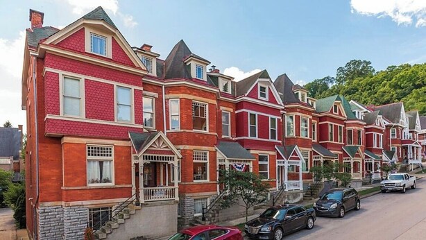 A row of red brick townhouses with gabled roofs and front porches.
