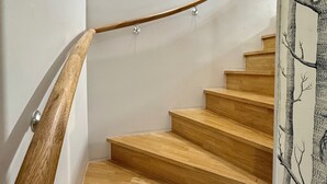 A wooden staircase with a handrail and a wall with a tree pattern.