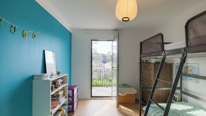 A room with a bunk bed, a bookshelf, a ladder, and a large window.