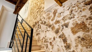 A staircase with a wooden handrail and stone walls.