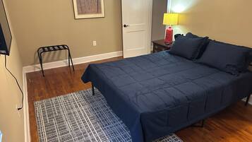 A bedroom with a bed, a nightstand, a lamp, and a door.
