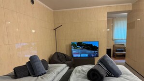 Camera d'albergo con due letti, televisione e vista sull'esterno.