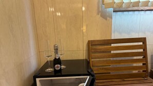Un minibar con una bottiglia di Martini e due bicchieri, una panca di legno e una parete rivestita di piastrelle.