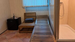 Una stanza piccola e funzionale con un letto, un tavolino con una bottiglia e uno spazio doccia.