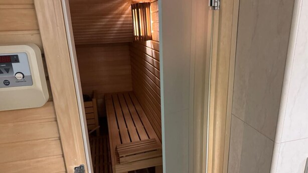 Una sauna con panche in legno e un pannello di controllo.