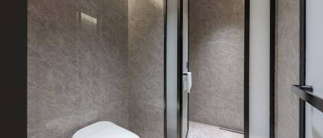 Un baño moderno con inodoro, ducha y puerta de vidrio.