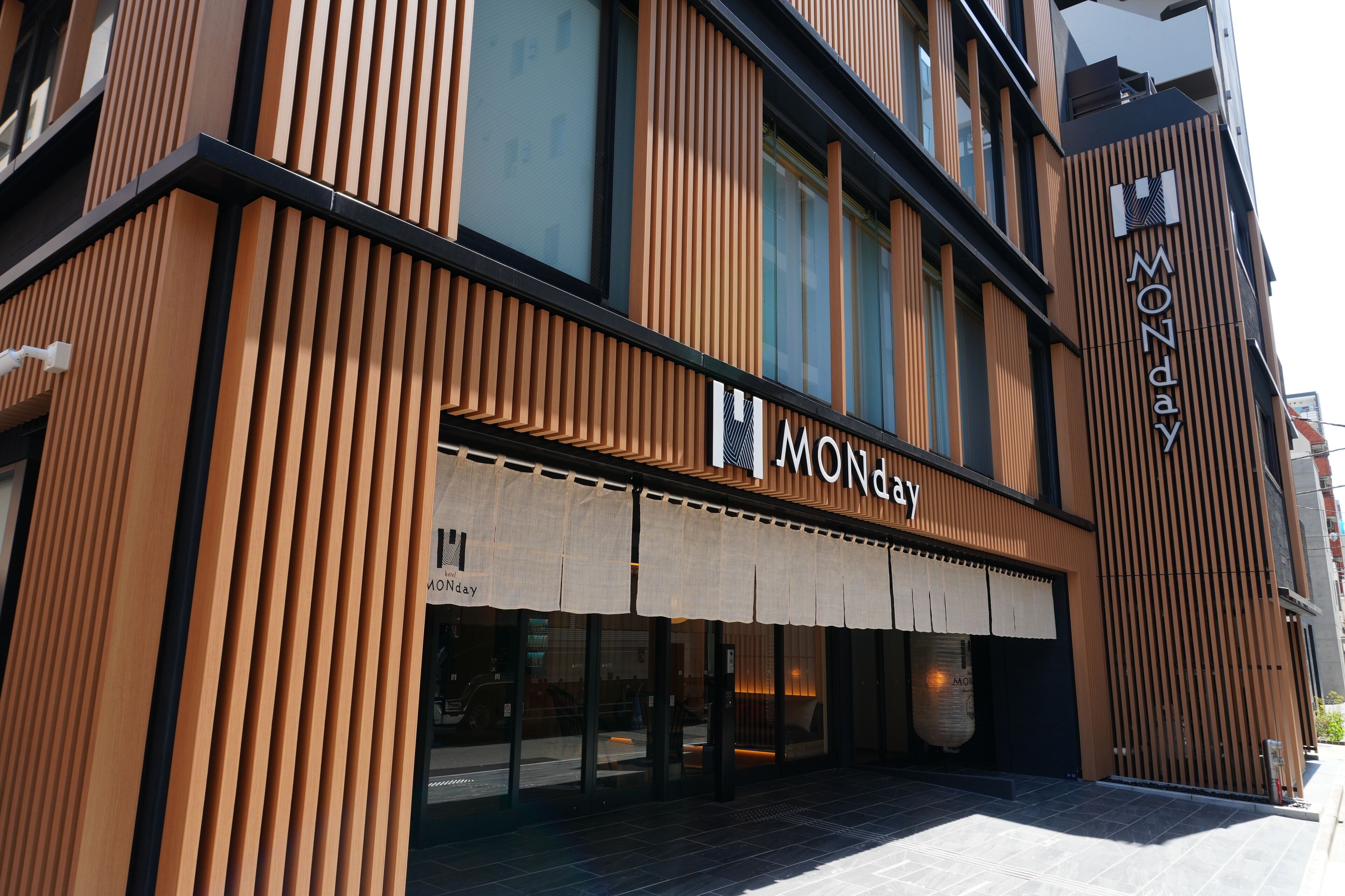A modern building with a prominent 'MONDAY' sign on the facade, featuring vertical wooden slats and large windows.