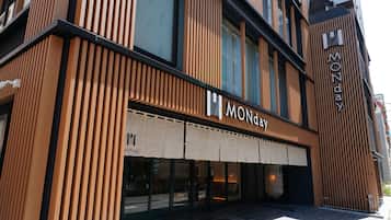A modern building with a prominent 'MONDAY' sign on the facade, featuring vertical wooden slats and large windows.