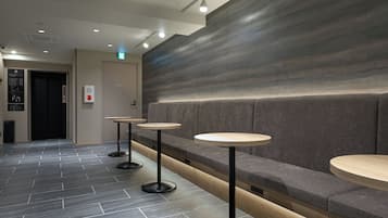 A modern interior with a seating area, three round tables, and a wall with a textured pattern.