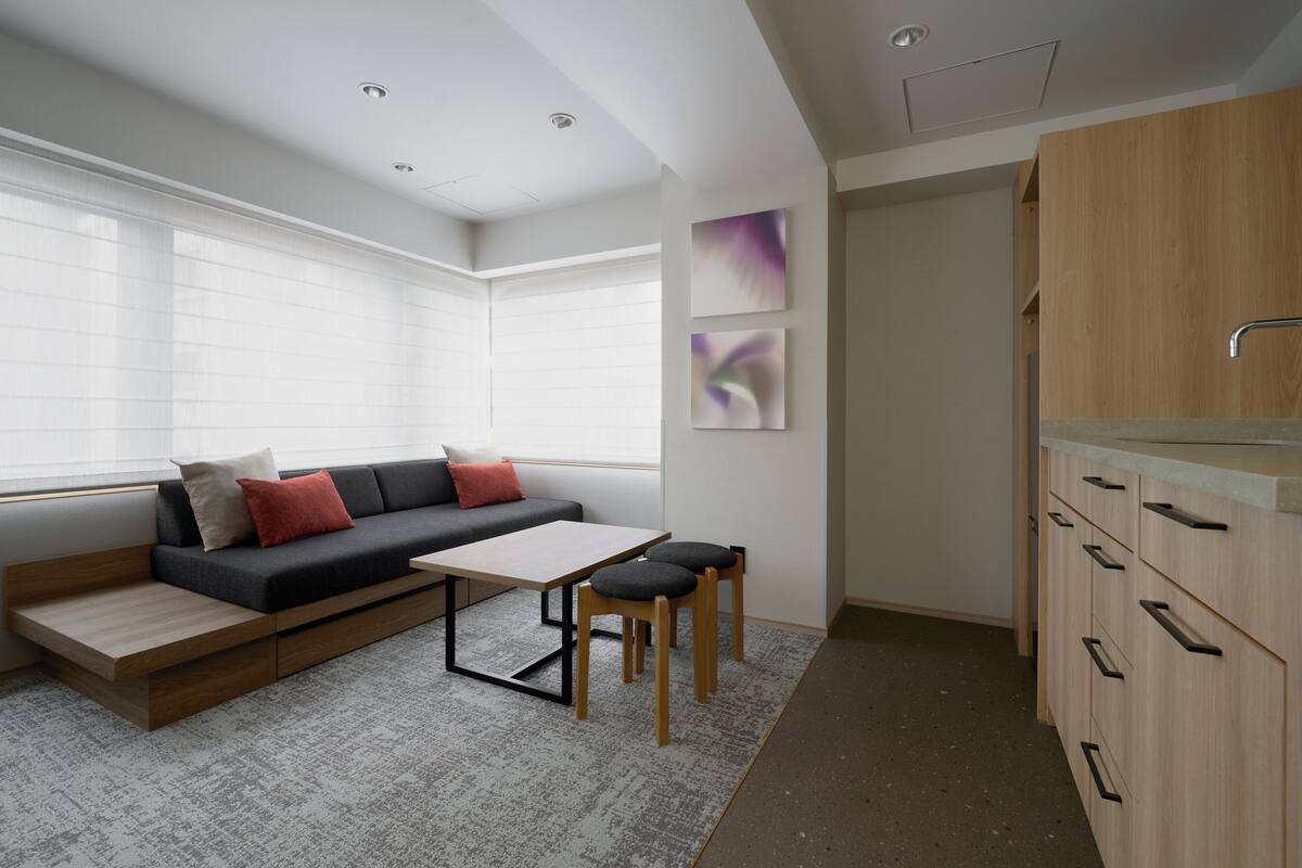 A modern kitchen with a built-in oven, wooden cabinets, a sink, and a window with blinds.