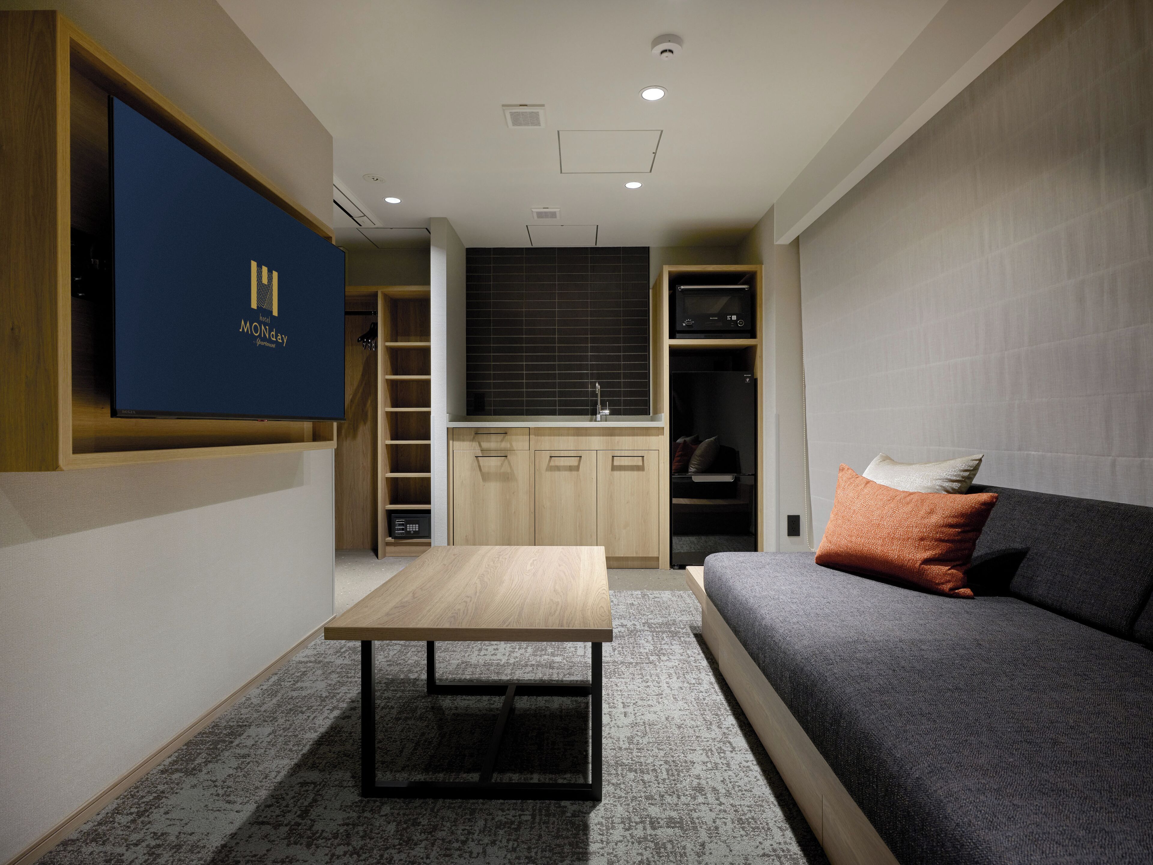 Una sala de estar moderna con un sofá, una mesa de centro y un televisor montado en la pared.