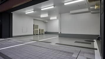 A spacious, well-lit indoor area with a tiled floor, ventilation ducts, and a large white wall.