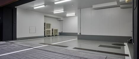 A spacious, well-lit indoor area with a tiled floor, ventilation ducts, and a large white wall.