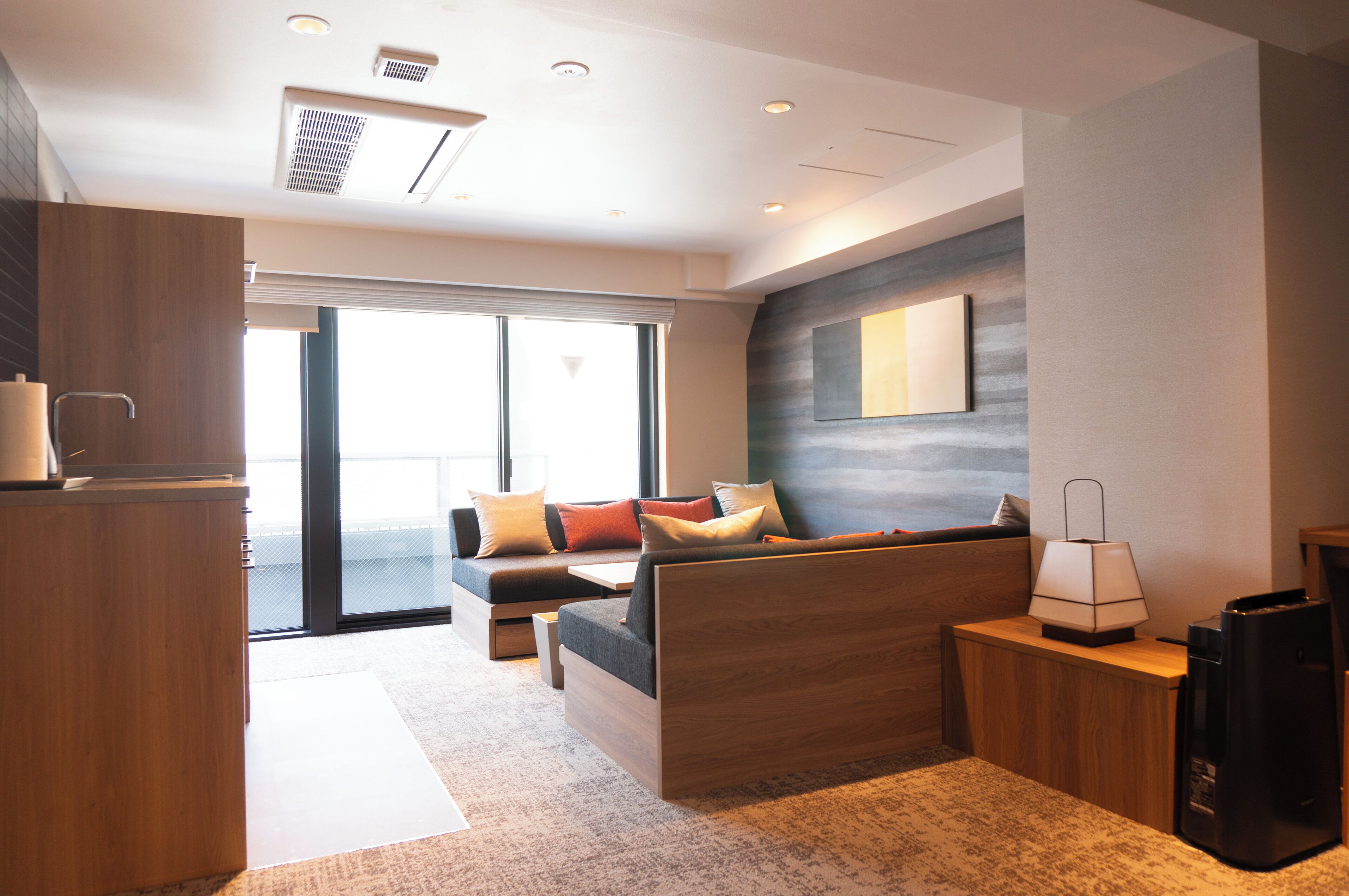 Ett modernt hotellrum med en soffa, ett litet bord, en lampa och utsikt över omgivningarna.