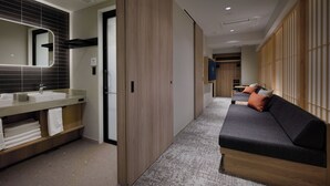 Une chambre d’hôtel moderne avec salle de bain, canapé et armoire en bois.