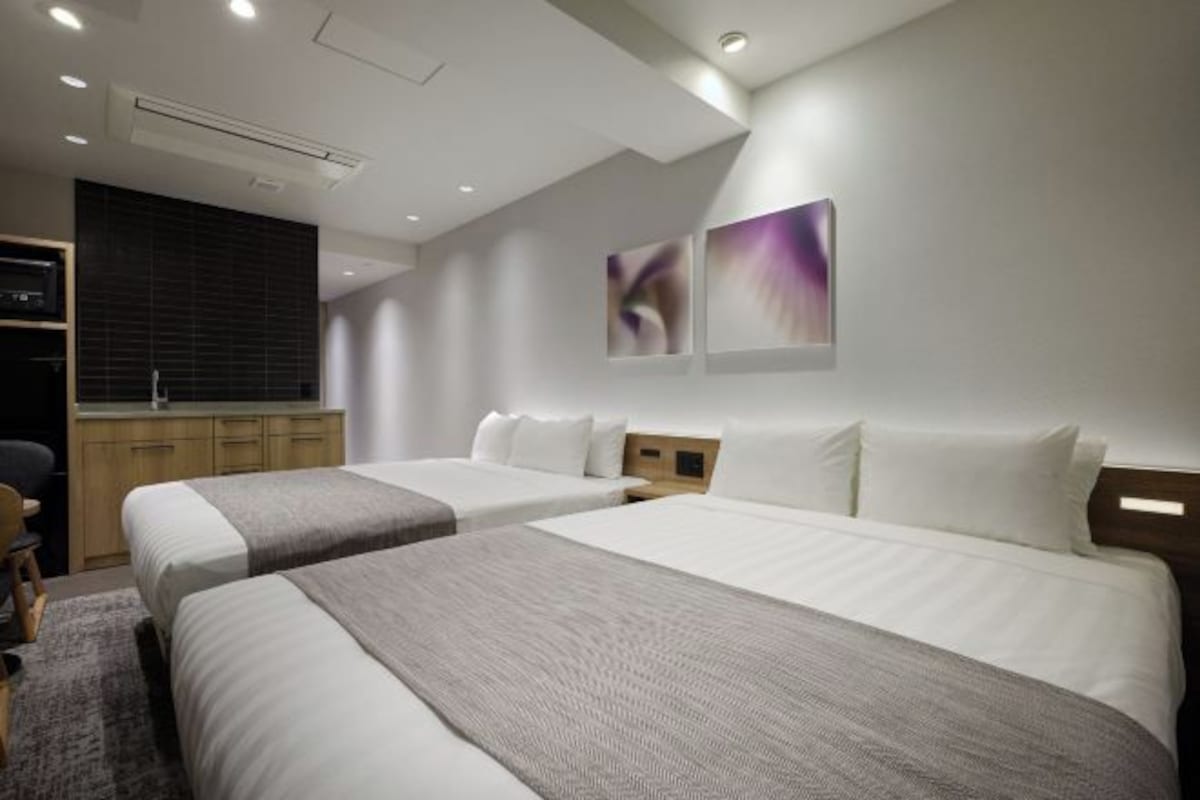 Una habitación de hotel con dos camas, un escritorio y un armario.