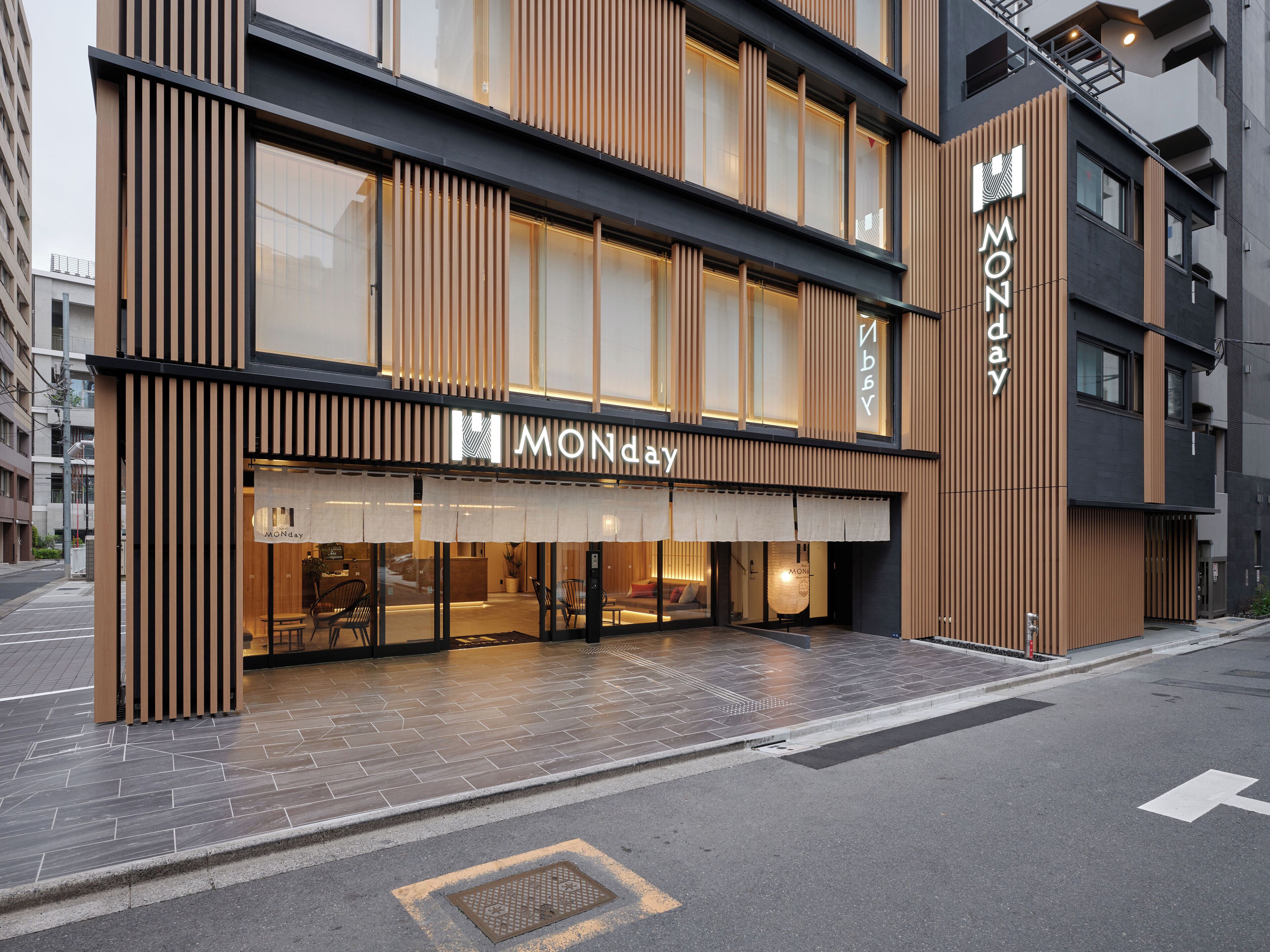 A modern hotel with a prominent 'MONday' sign, large windows, and a clean, tiled entrance area.