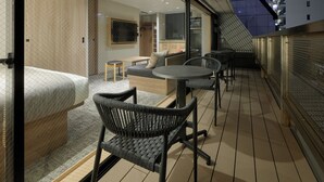 Une chambre d’hôtel moderne avec balcon, meublée d’un canapé, de fauteuils et d’une petite table.