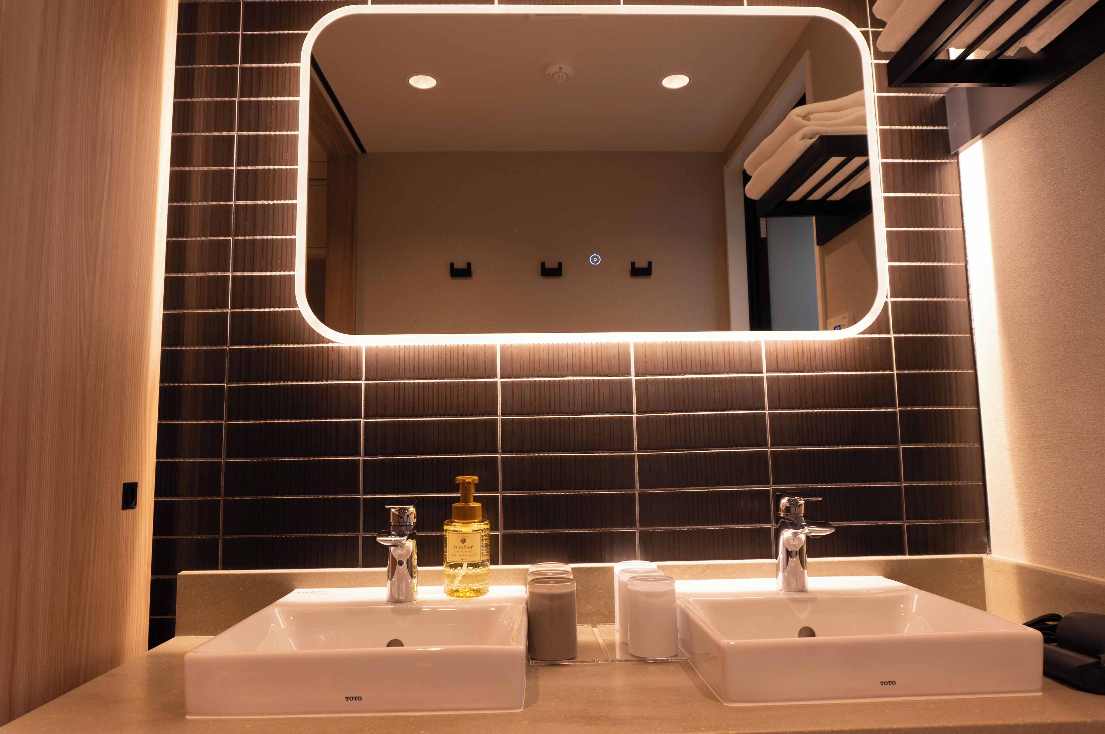 Un bagno moderno con due lavabi, uno specchio grande e un porta asciugamani.