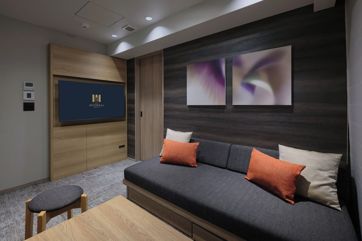 A modern living room with a sofa, a TV, and a wooden cabinet.