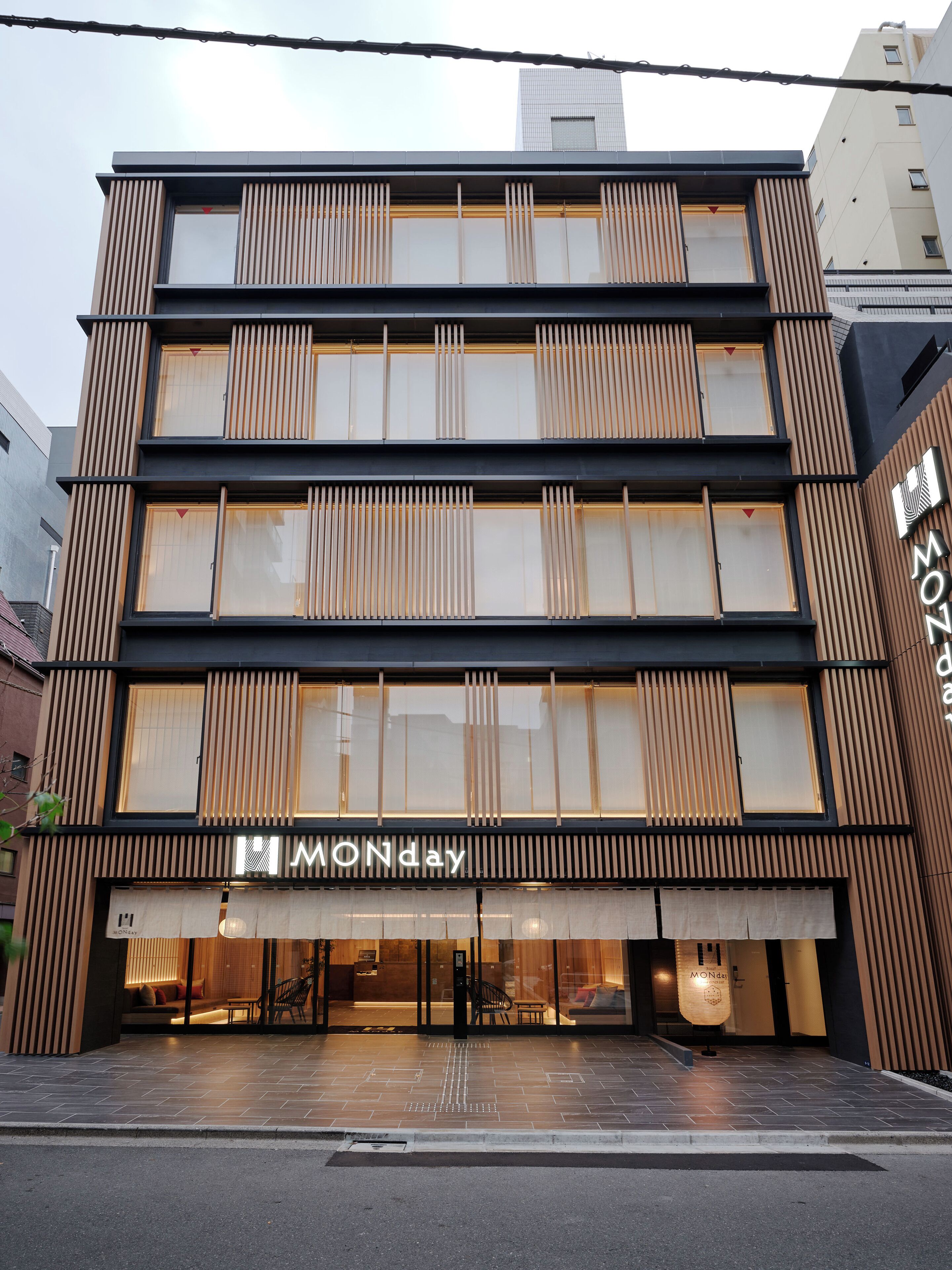A modern building with a prominent "MONday" sign, featuring a clean, contemporary design with vertical wooden slats and large windows.