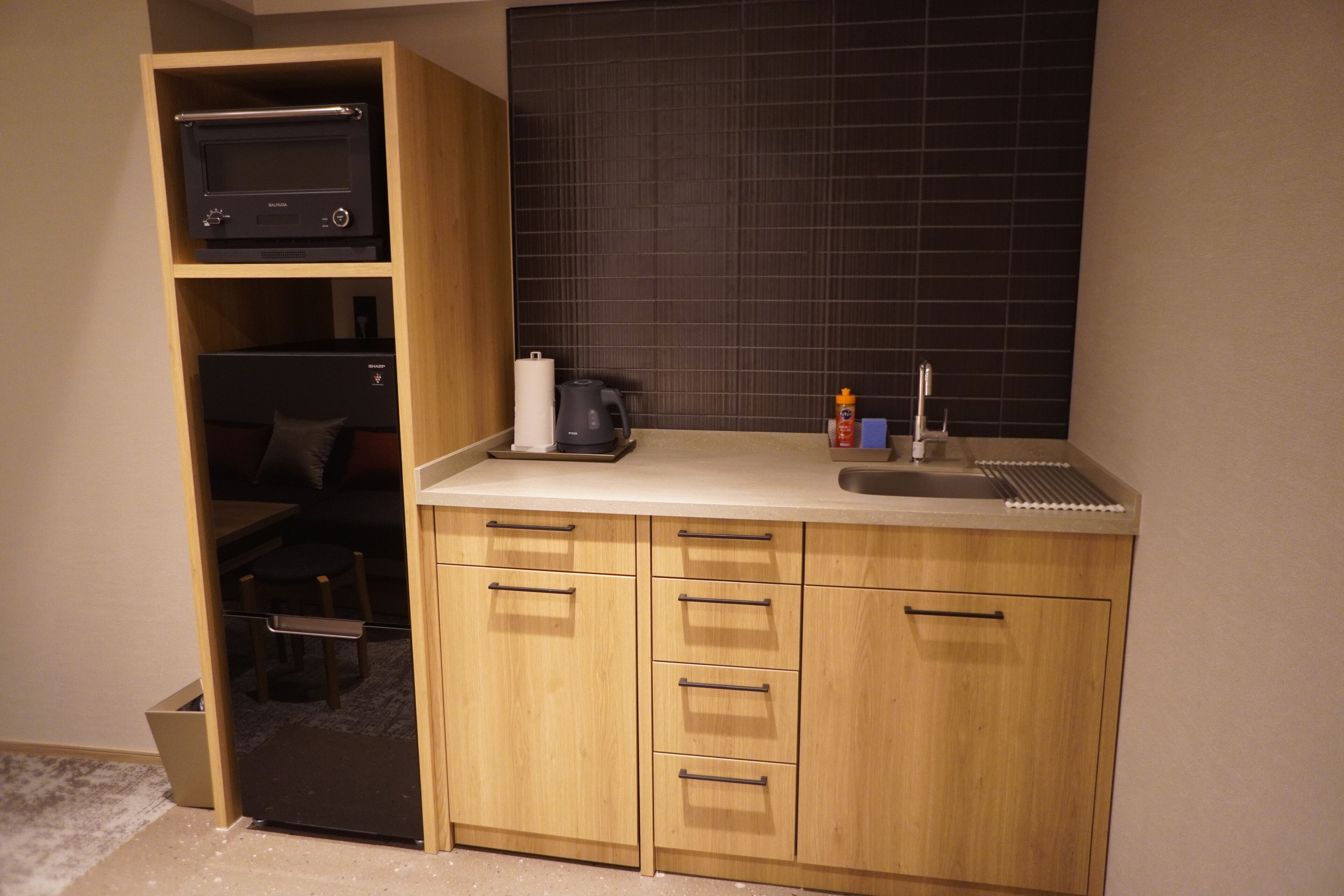 A compact kitchen with wooden cabinets, a countertop, a coffee maker, and a microwave.