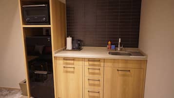 A compact kitchen with wooden cabinets, a countertop, a coffee maker, and a microwave.