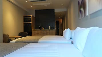 A hotel room with a large bed, a desk, a chair, a kitchenette, and a bathroom.