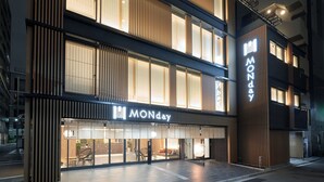 Un hôtel moderne, reconnaissable à son grand panneau « MONDAY », à ses larges fenêtres et à son hall d’entrée bien aménagé.