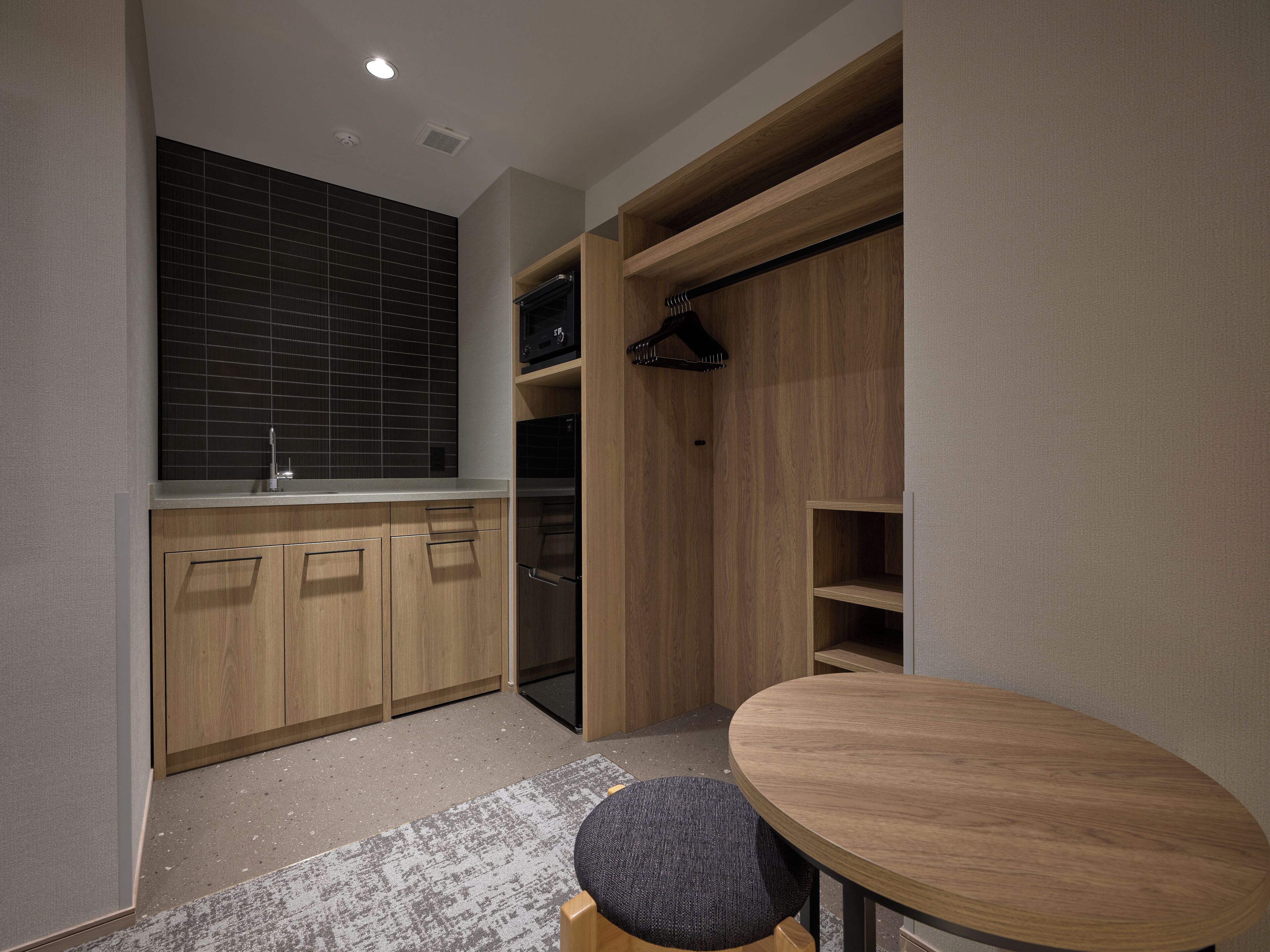 Cocina compacta con armarios de madera, horno integrado y un pequeño comedor con una mesa redonda.
