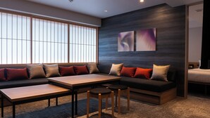 Un salon moderne avec un canapé d’angle, une table basse en bois et deux tabourets de bar.