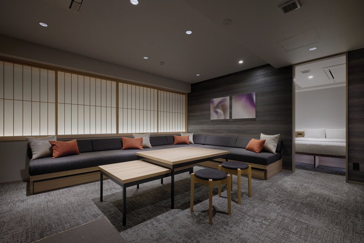 A modern living room with a sectional sofa, a wooden coffee table, and a small dining table.