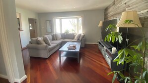 A living room with a sectional sofa, a coffee table, a TV, and a lamp. - Entire Home in Toronto - 10 mins YYZ (Toronto)