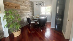 A dining area with a wooden wall, a dining table with chairs, a hanging light fixture, and a potted plant. - Entire Home in Toronto - 10 mins YYZ (Toronto)