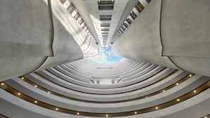 Un intérieur architectural moderne, doté d’un escalier en colimaçon central et d’une verrière au sommet.