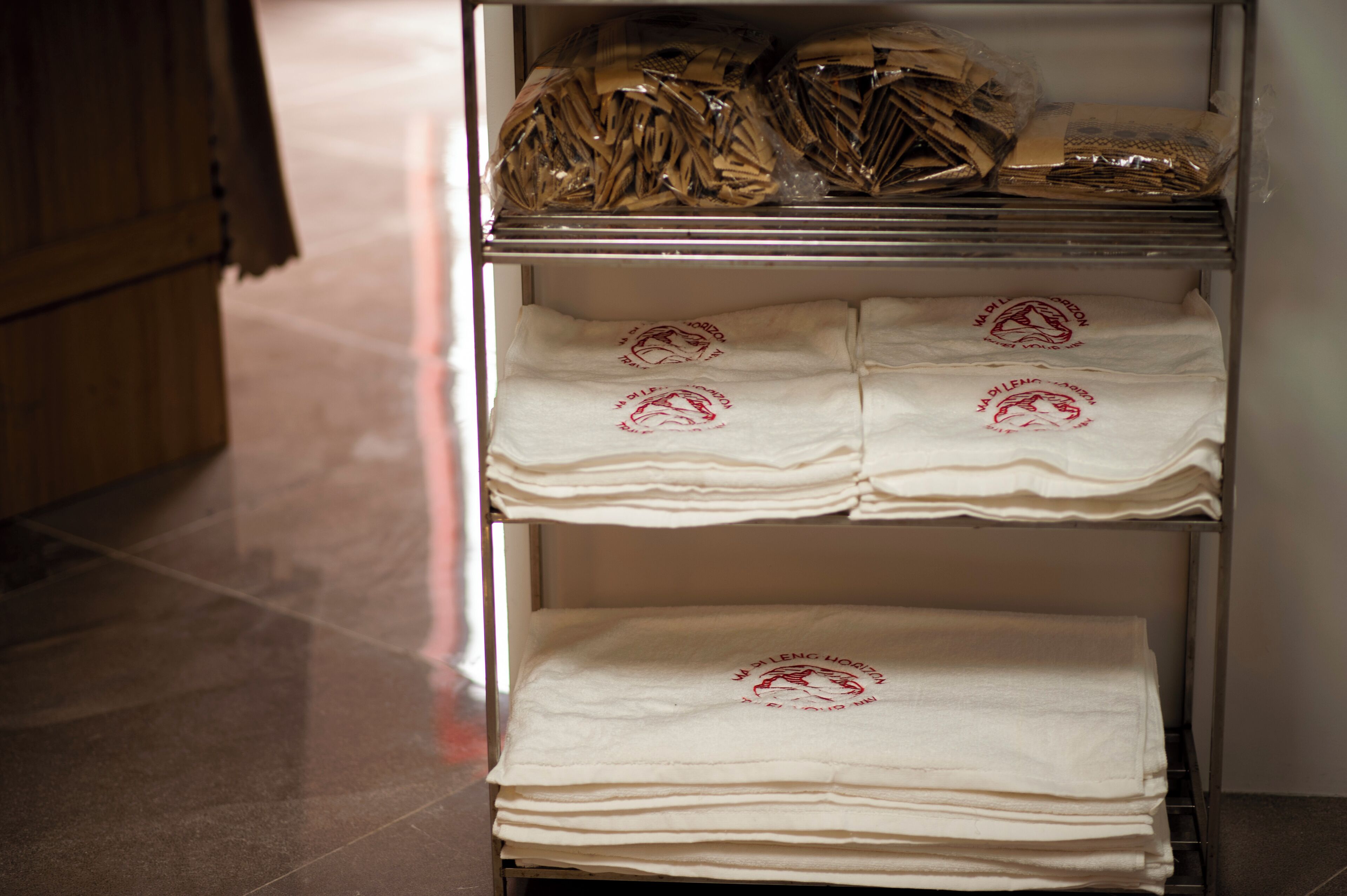 A storage unit with neatly stacked white cloths and bags.