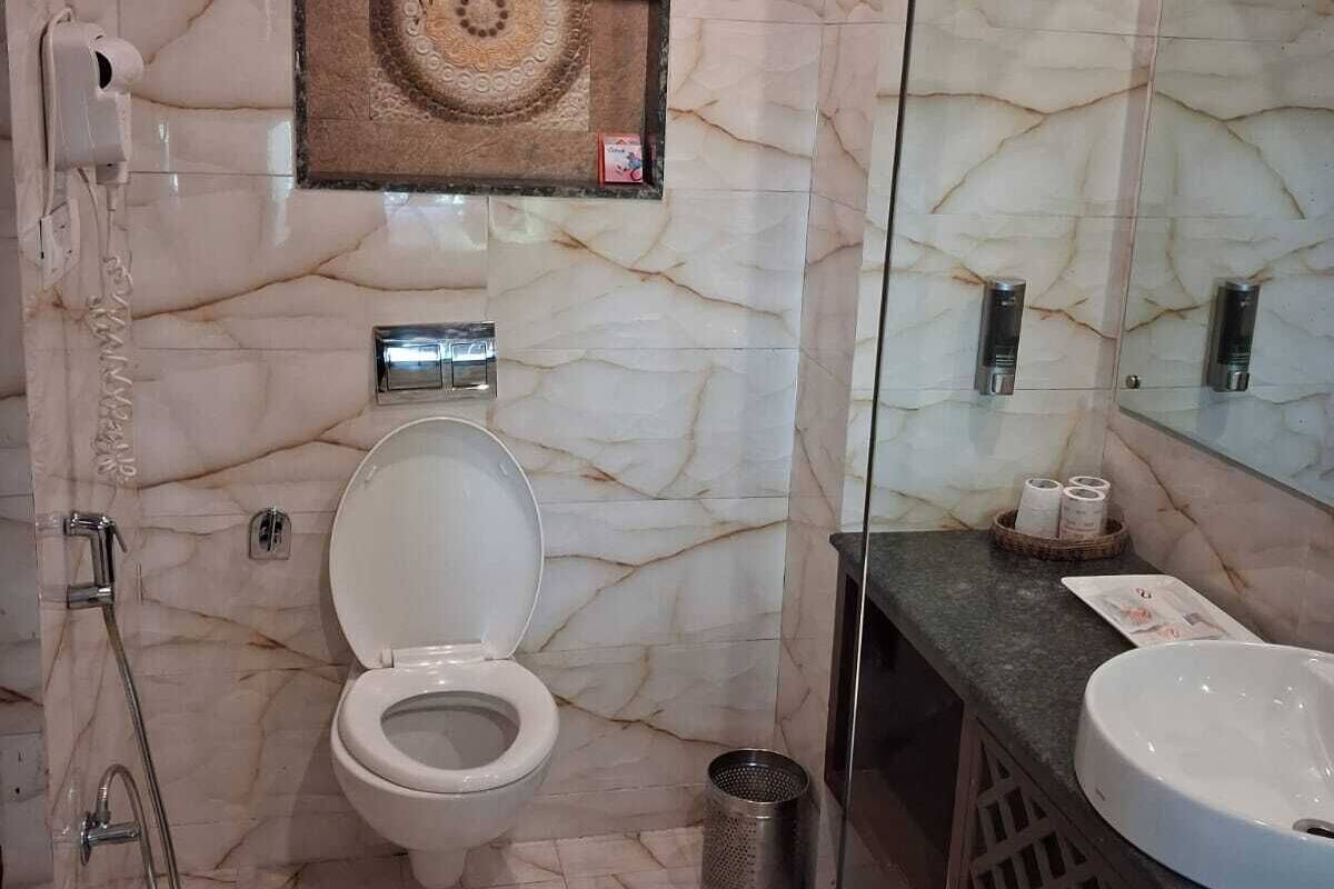 A bathroom with a marble floor, a toilet, a shower, a sink, and a mirror.