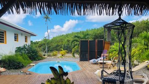 A wooden deck with a pool, lounge chairs, and a table with bananas. - Villa Kaz à Colibri with swimming pool for a relaxing break with family or friends (Unknown)
