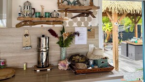 A kitchen with wooden shelves, a coffee maker, decorative items, and a view of the outdoor area. - Villa Kaz à Colibri with swimming pool for a relaxing break with family or friends (Unknown)