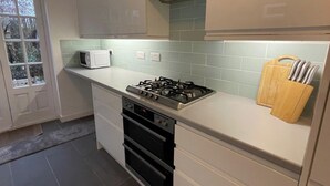 A kitchen with a gas stove, oven, microwave, and a window with a view of trees.