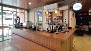 Una zona de bar moderna con mostrador de madera, una máquina de café y un cartel que anuncia un descuento del 20%.
