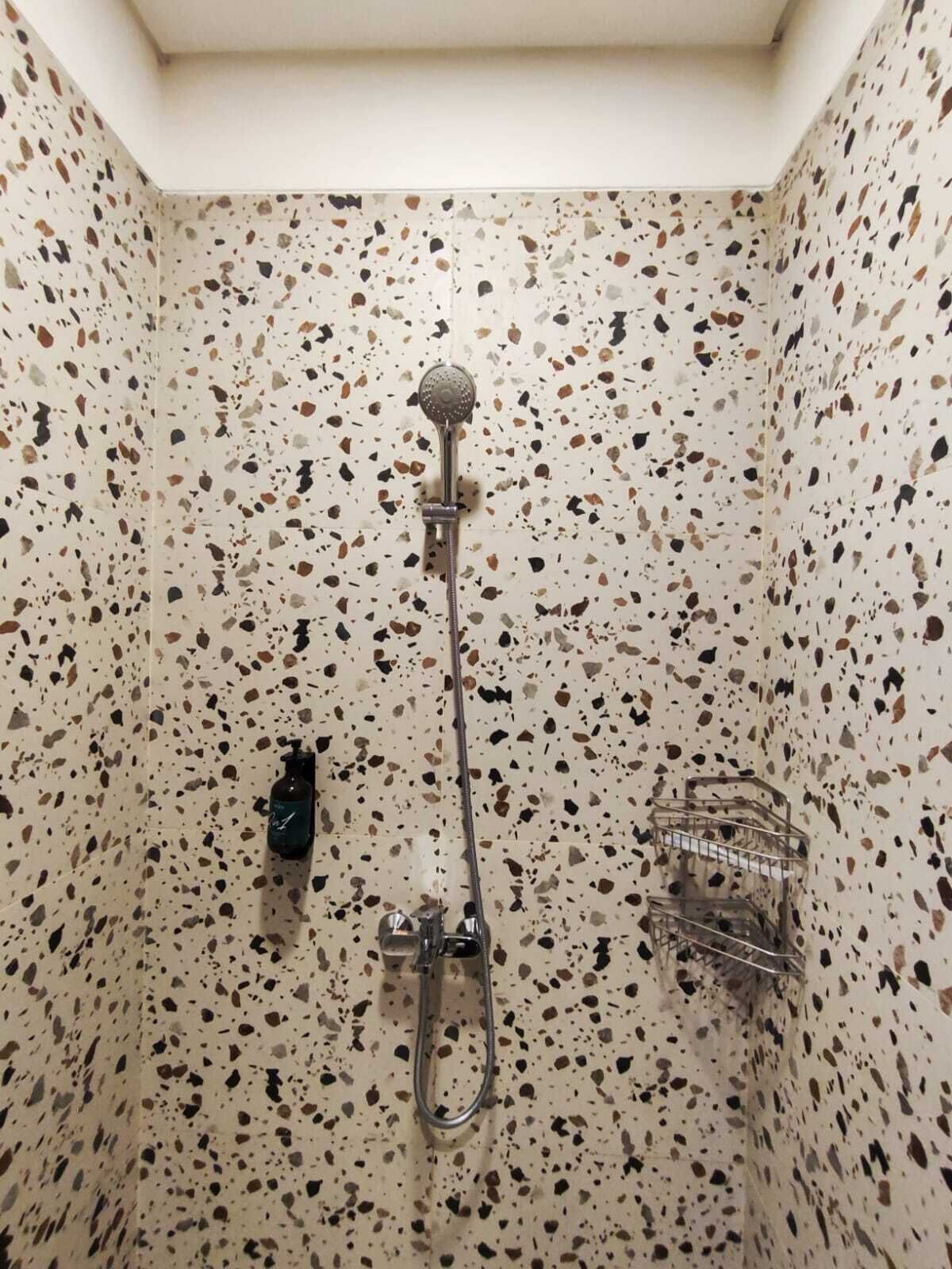 A shower with a handheld showerhead and a handheld shower attachment.